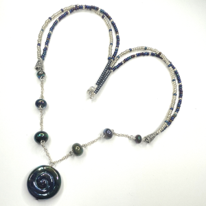 A necklace featuring handmade lampwork beads with a doble strand of seed beads attached