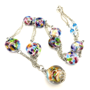 A necklace with handmade lampwork beads that show speckles of coloured flecks in them. Each bead is joined by sterling silver chains.